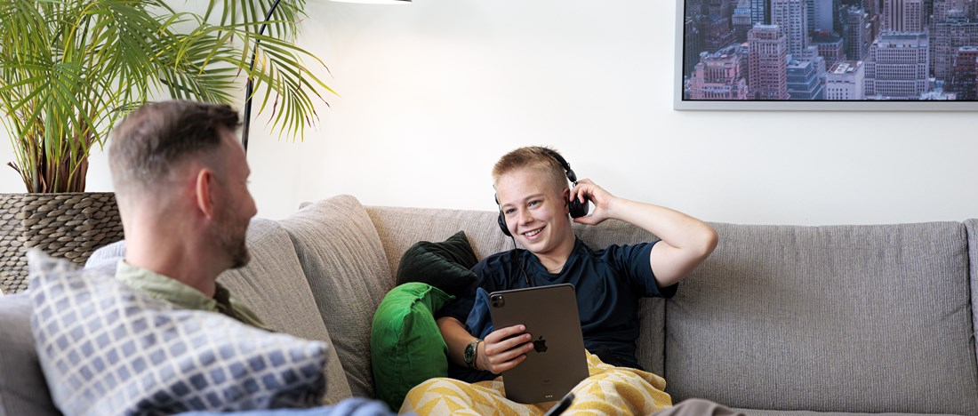 Man sitter och pratar med sitt barn i en soffa.