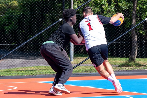 två ungdomar spelar basket på en basketplan