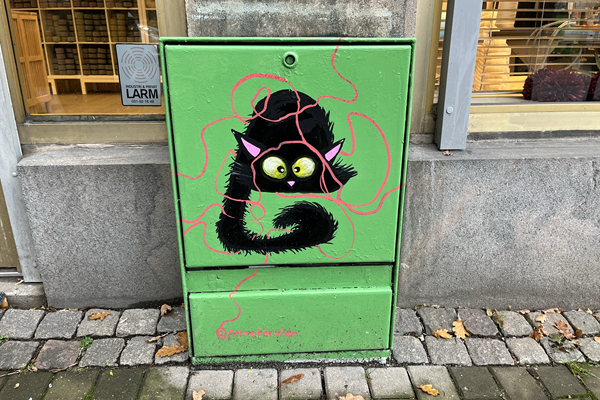 Målat elskåp föreställande en svart katt brevid ett rött garnnystan