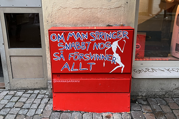 Ett målat elskåp med röd botten och vit text "Om man springer tillräckligt snabbt försvinner allt"