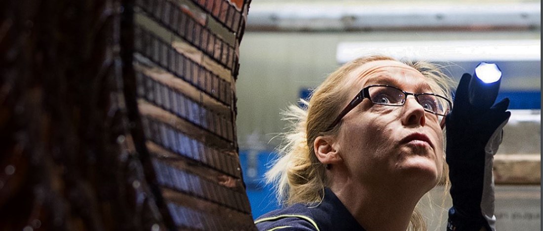 En kvinna som inspekterar en maskin.