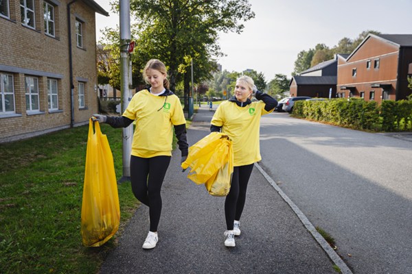två ungdomar ute i Städa Sverige tröjor och samlar in skräp.