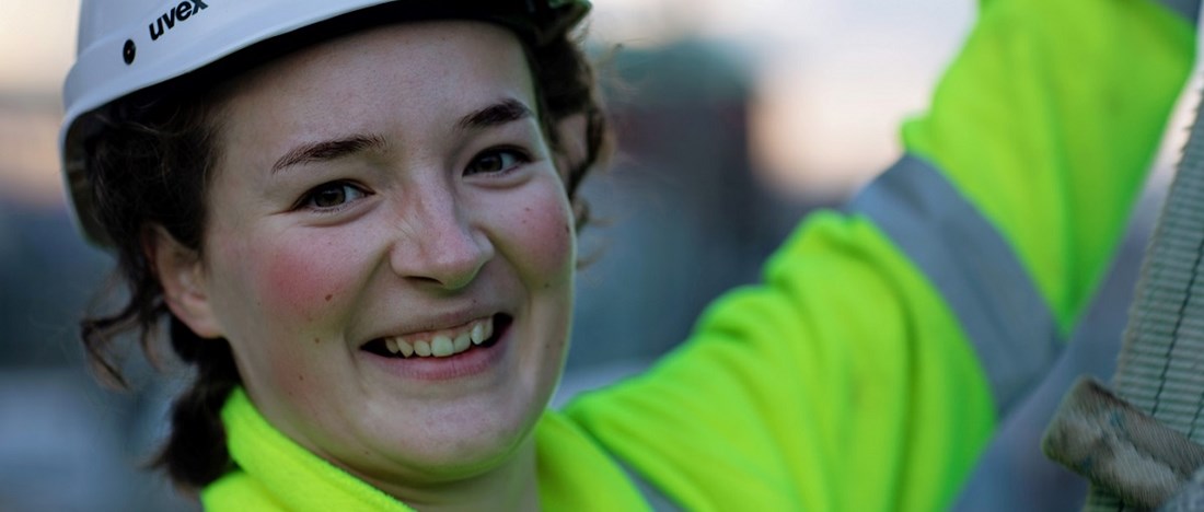 Julia bärandes arbetskläder ler mot kameran.