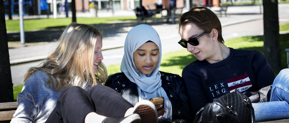 Fyra ungdomar sitter på en bänk utomhus