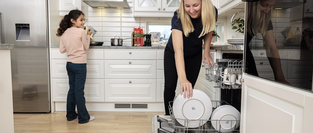 En kvinna och ett barn ställer in disk i diskmaskinen.