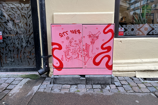 Målat elskåp i rött och rosa med texten "sitt ner"