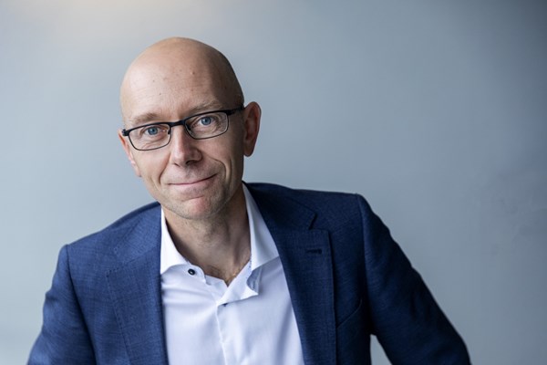 En man i kavaj ler mot kameran.