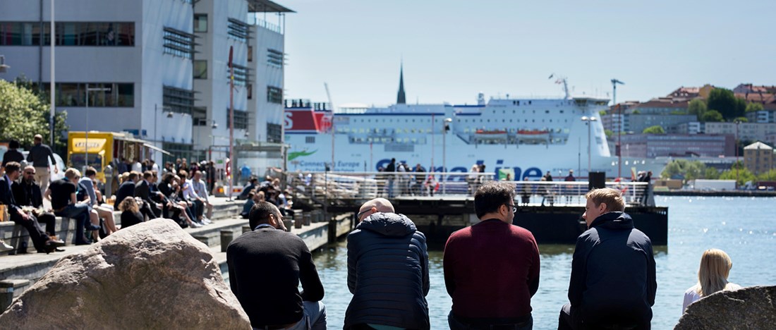 Lindholmen, personer sitter på brygga och ser ut över vattnet.