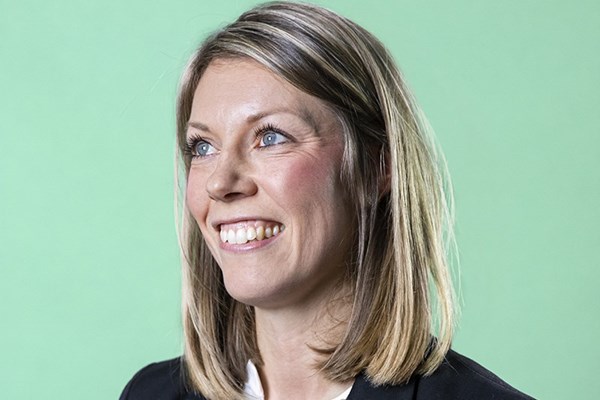 Göteborg Energis emdarbetare Therese står i profil till kameran, fotograferad i studio med grön bakgrund.