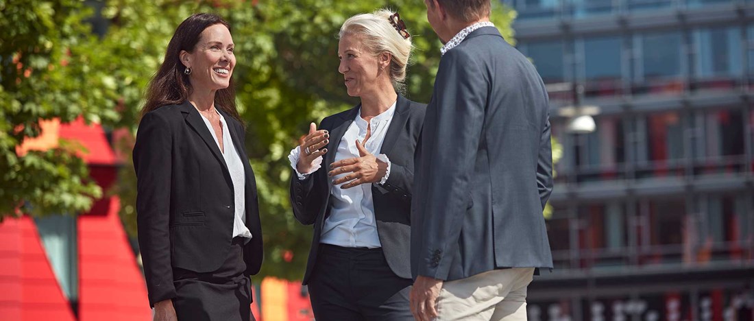 Tre personer står och pratar utomhus