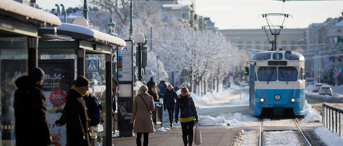 Kungsportsplatsen spårvagnshållplats mitt i vintern, snöig stadsmiljö, treans spårvagn på väg mot kameran.