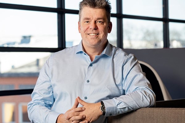 En man i ljusblås skjorta ler mot kameran.