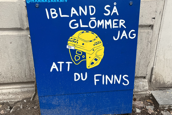 Ett målat elskåp på järntorget med blå bakgrund och en gul hockeyhjälm