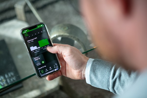 man håller i en smartphone som visar statistik över elanvändning