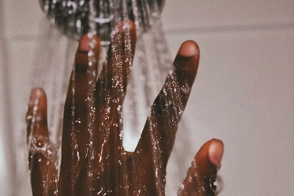 En hand låter vatten från en dusch strila mellan fingrarna.