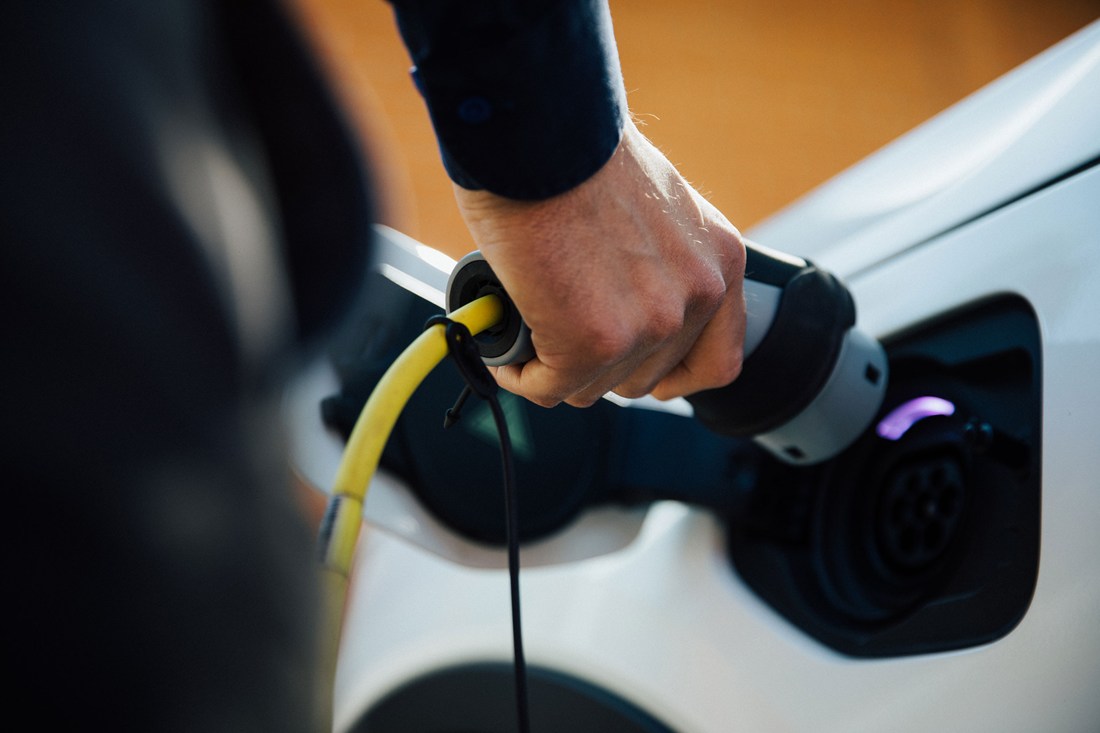 En hand kopplar in en laddare i en elbil. 