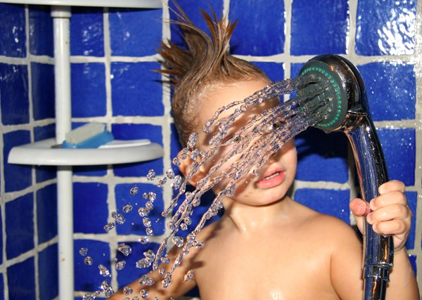 Ett barn leker med duschstrålen.